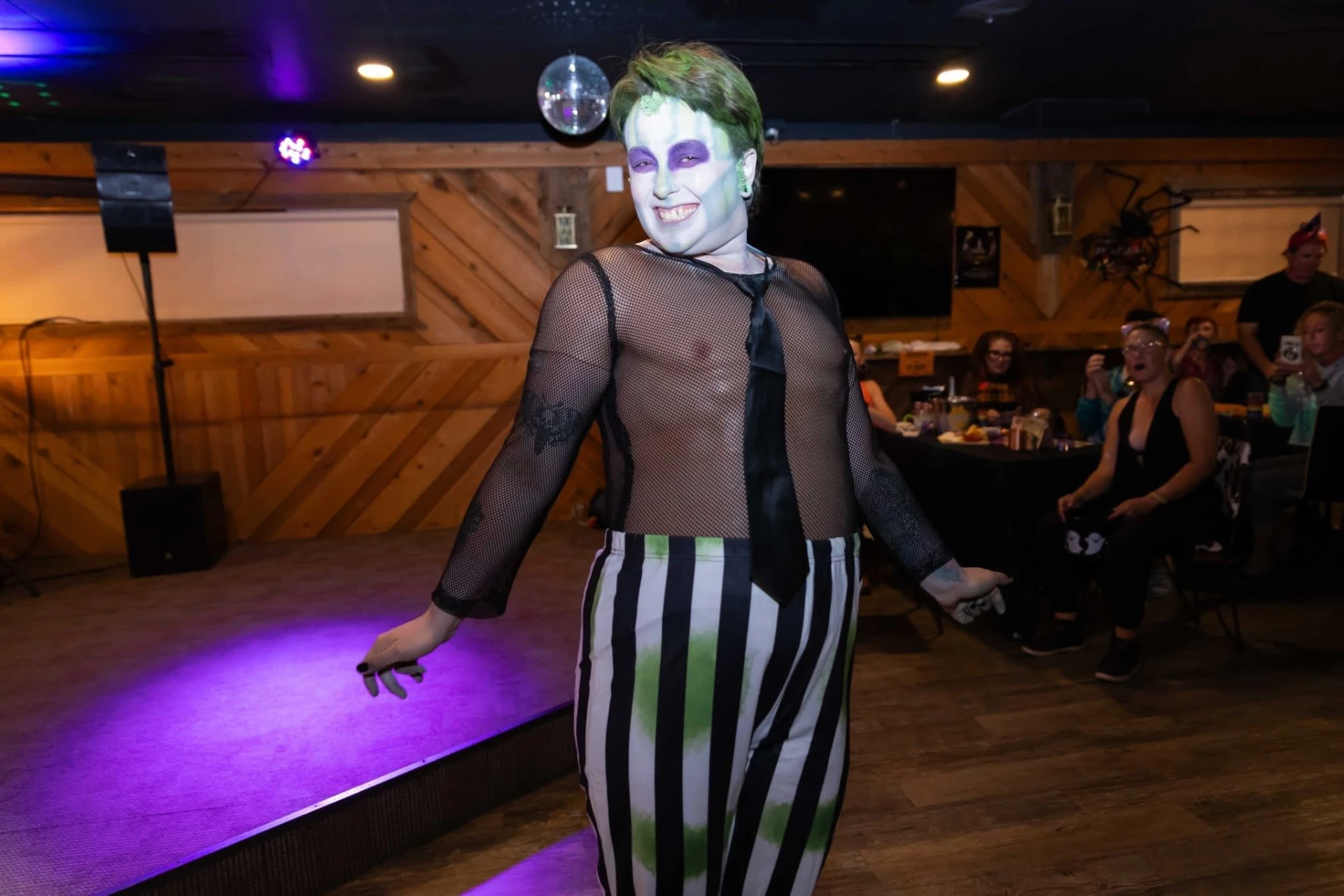 Drag performer in striped costume on the dance floor