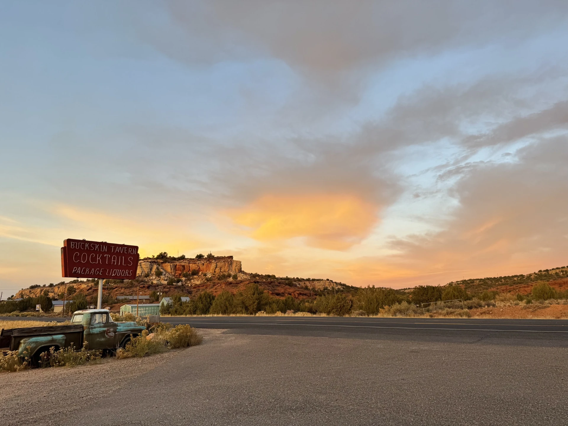 Buckskin Tavern cocktails sign at sunset with a vintage truck
