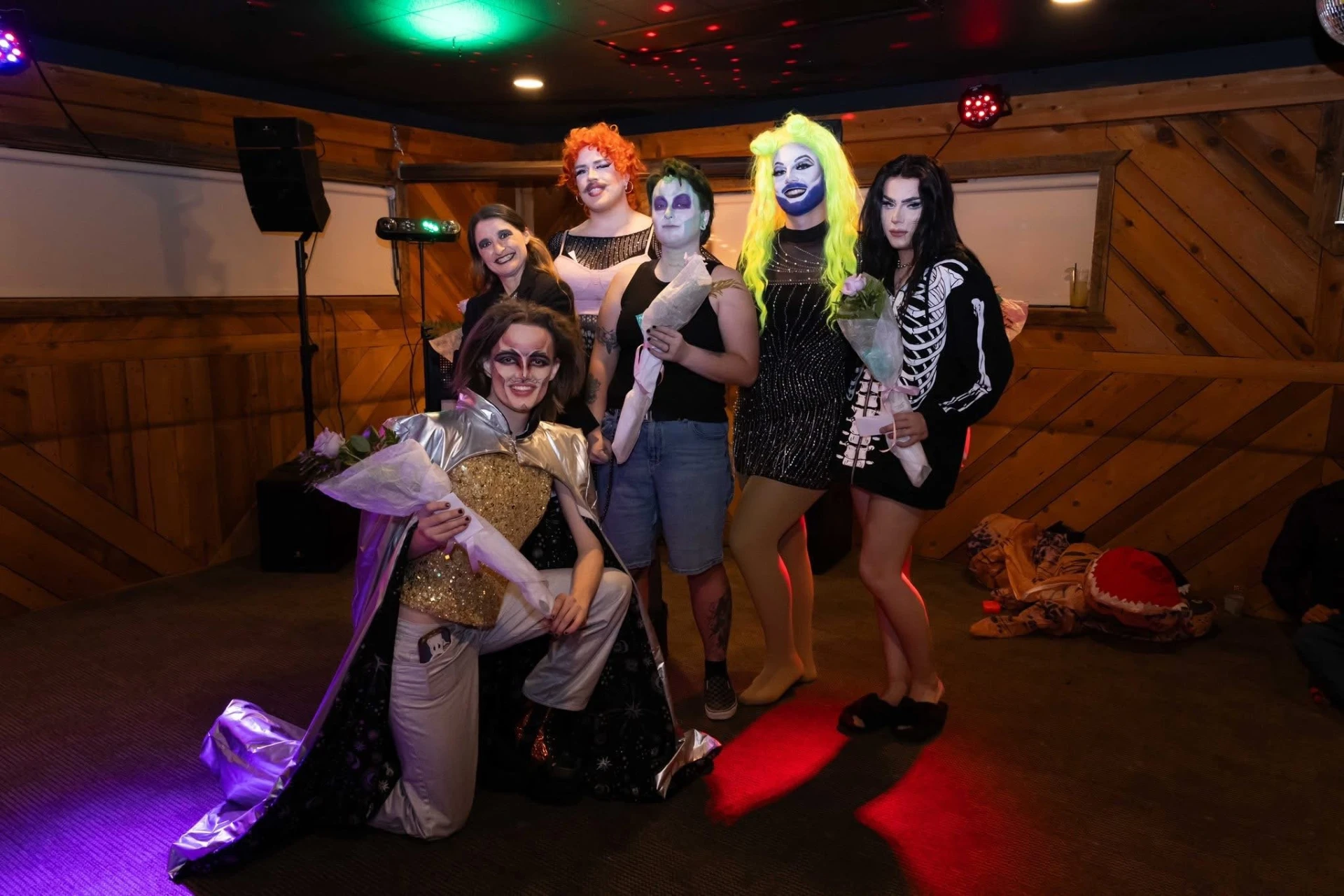 Drag show cast posing together with bouquets